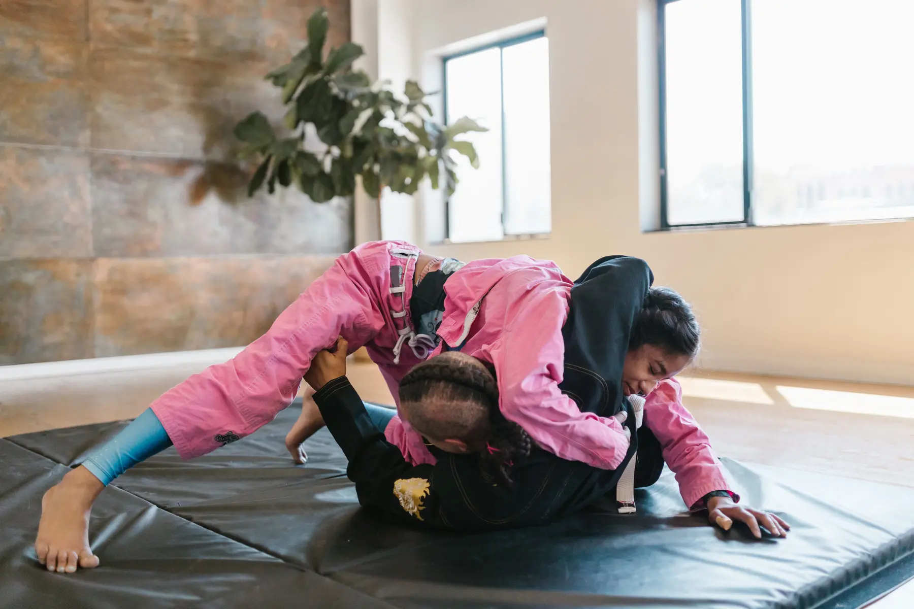 Two women practicing Brazilian jiu-jitsu on a mat